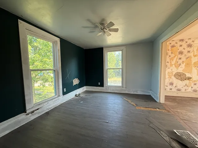 a view of an empty room with a window and wooden floor