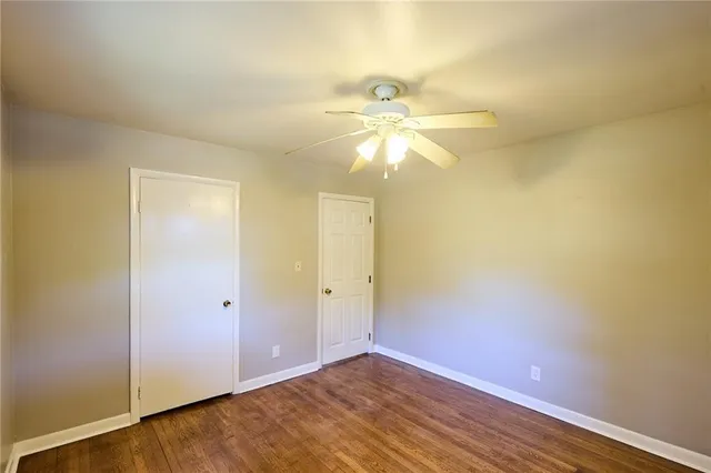 an empty room with wooden floor and fan