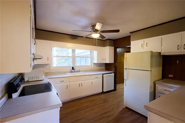 a kitchen with a refrigerator a sink dishwasher and a stove with wooden floor