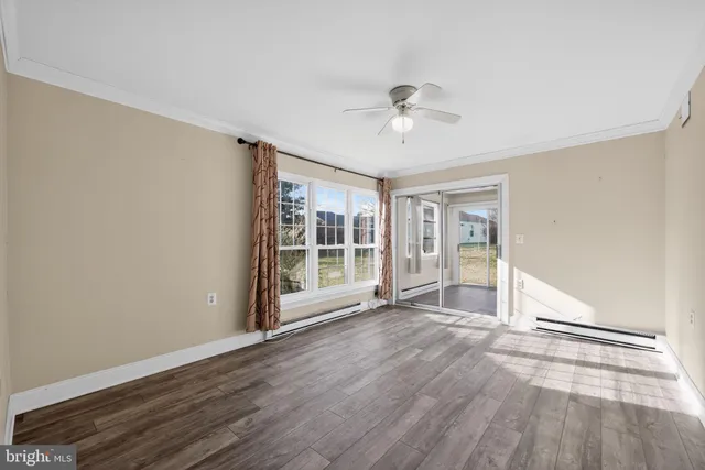 a view of an empty room with a window and wooden floor
