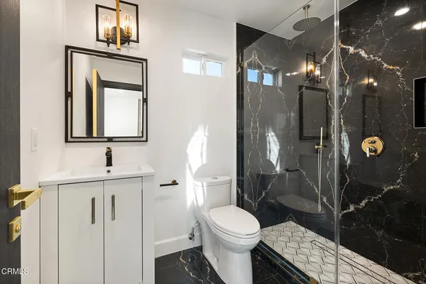 a bathroom with a toilet a sink a shower and mirror