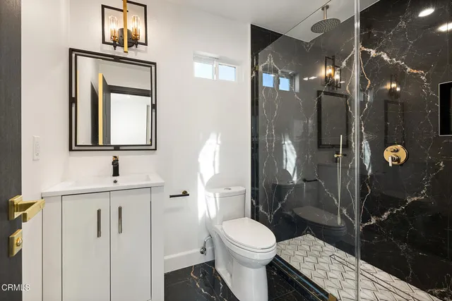 a bathroom with a toilet a sink a shower and mirror