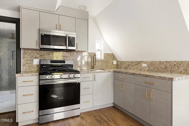 a kitchen with granite countertop a stove a sink and a microwave