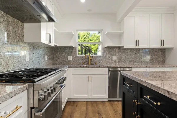 a kitchen with granite countertop a sink a stove and cabinets