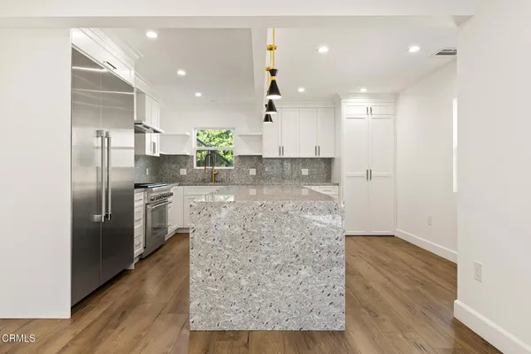 a kitchen with stainless steel appliances kitchen island granite countertop a refrigerator and a sink