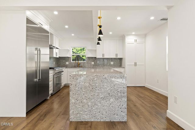a kitchen with stainless steel appliances kitchen island granite countertop a refrigerator and a sink