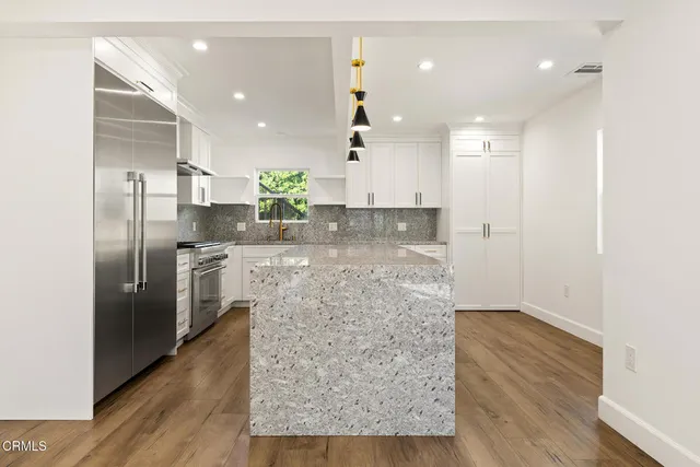 a kitchen with stainless steel appliances kitchen island granite countertop a refrigerator and a sink