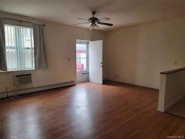 an empty room with wooden floor chandelier fan and windows