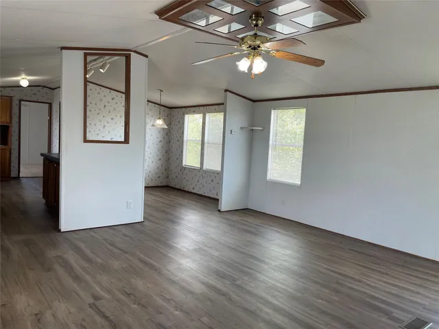 a view of an empty room with a window and wooden floor