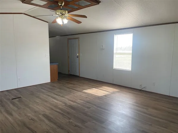 an empty room with wooden floor fan and windows