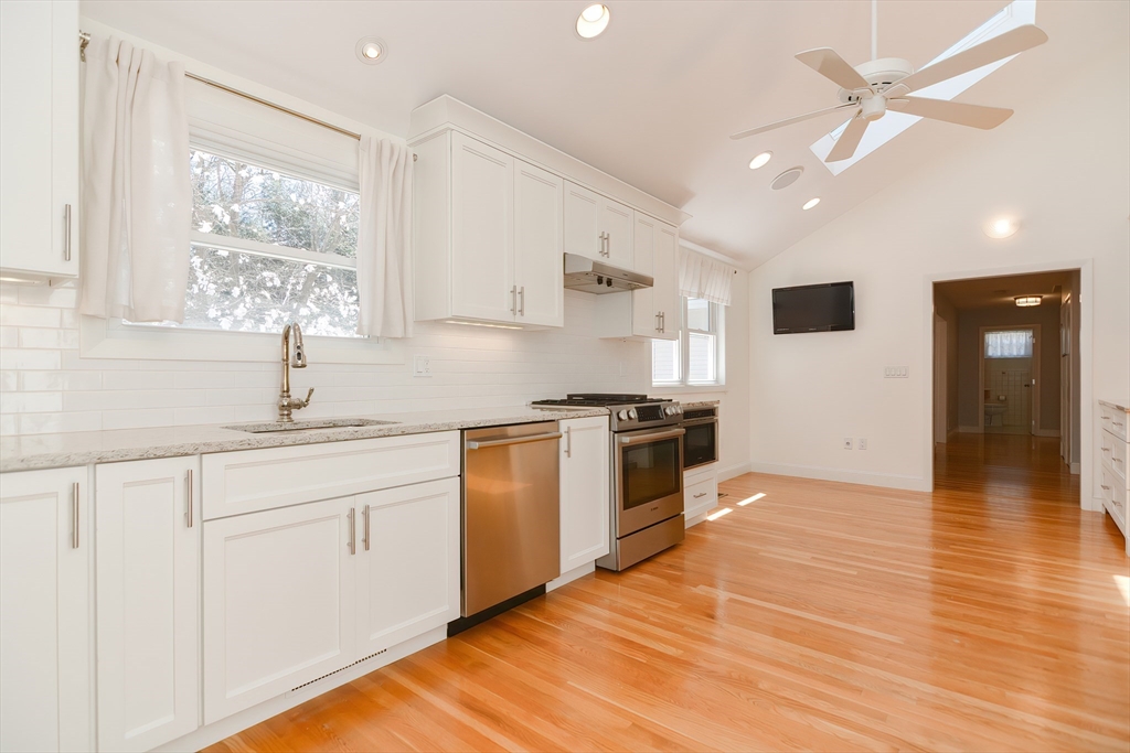 2054 Main Street Concord, MA 01742 - Photo 10 of 41 a kitchen with granite countertop a stove a sink and white cabinets with wooden floor