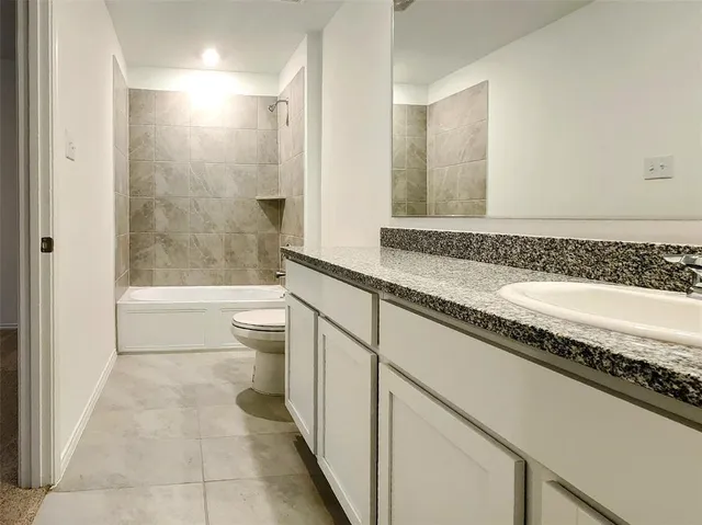 a bathroom with a granite countertop sink a toilet a mirror and bathtub