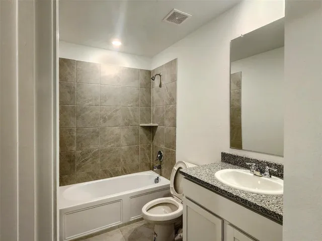 a bathroom with a granite countertop sink a toilet and bathtub