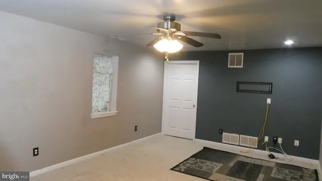a view of an empty room with a chandelier fan and a bathroom