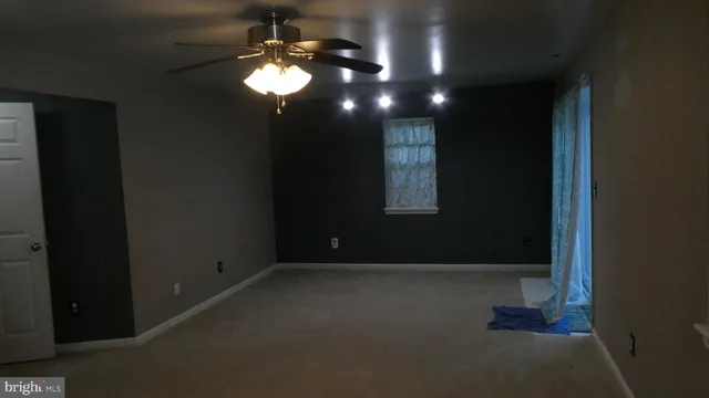 a view of an empty room with a chandelier fan