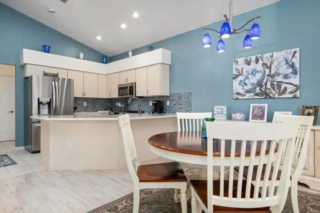 a kitchen with kitchen island granite countertop a dining table chairs sink and cabinets