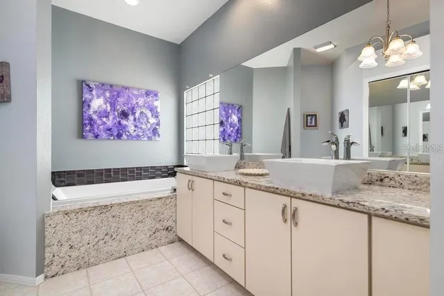 a bathroom with a granite countertop sink a large mirror and a bathtub