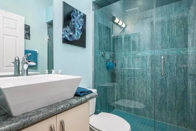 a bathroom with a granite countertop sink toilet a mirror and shower