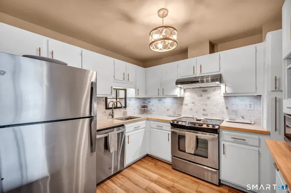 a kitchen with stainless steel appliances a refrigerator a stove and white cabinets