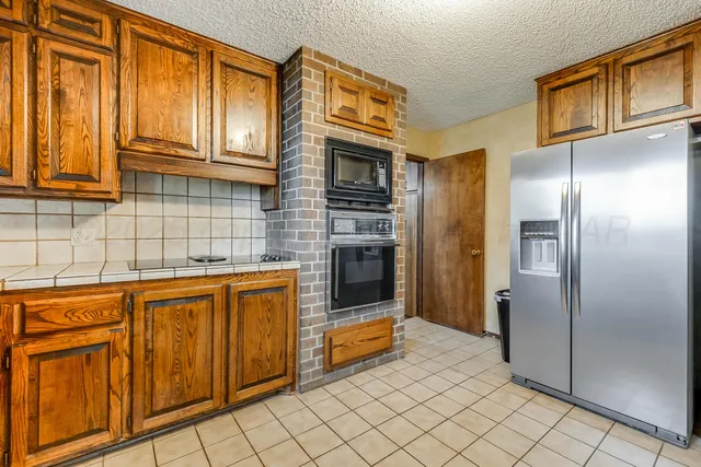 a kitchen with stainless steel appliances granite countertop a refrigerator and a stove top oven
