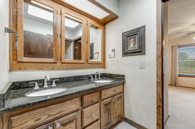 a bathroom with a granite countertop sink and a mirror