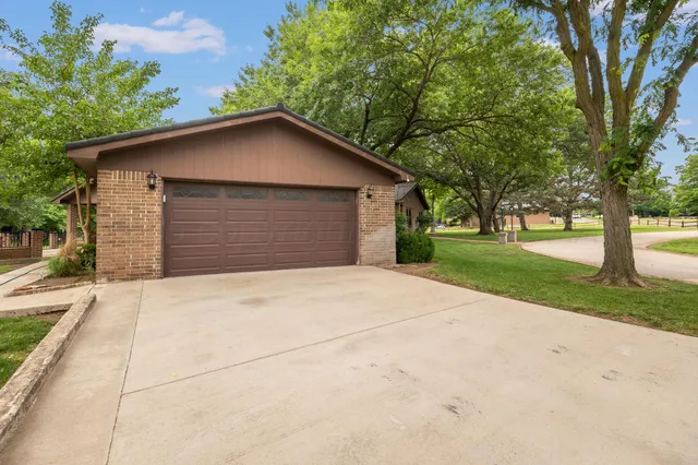 front view of house with a yard and trees all around