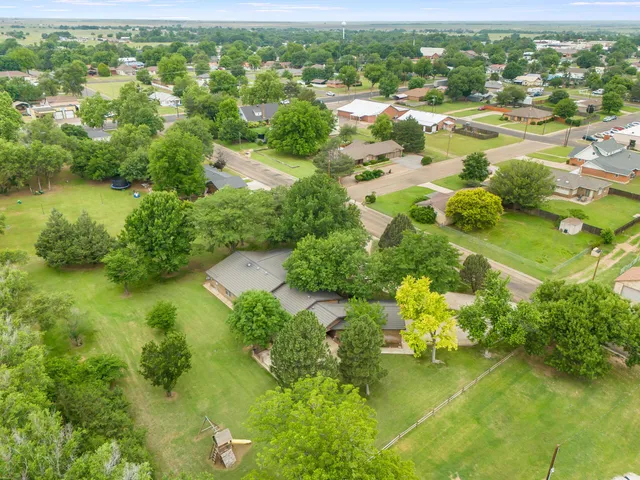 an aerial view of residential houses with outdoor space and trees all around