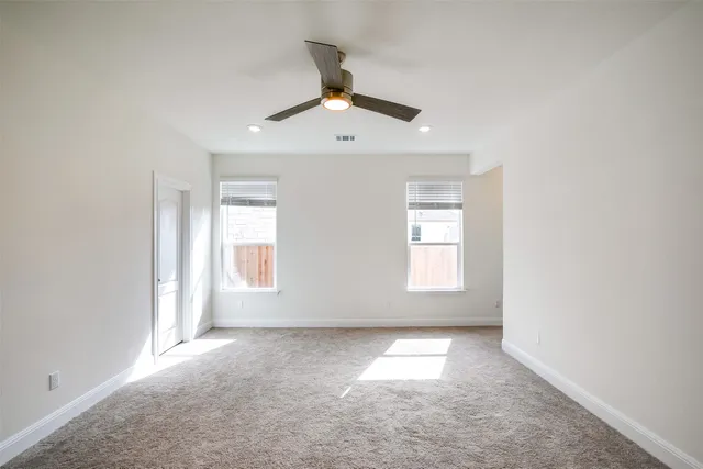 an empty room with a window and a ceiling fan