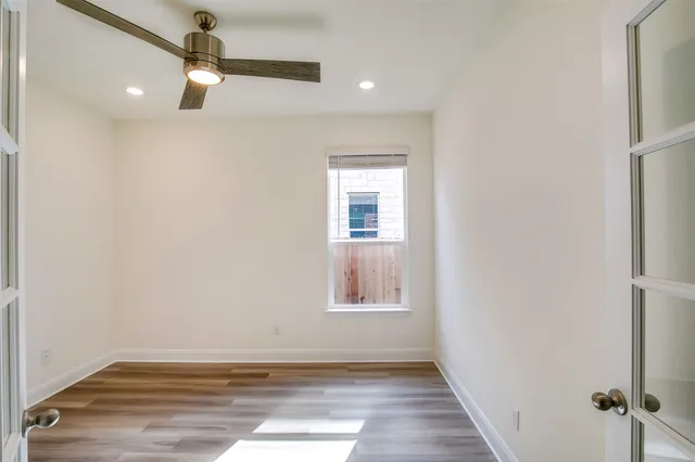 an empty room with wooden floor fan and windows