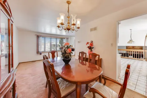 a view of a dining room with furniture a chandelier and wooden floor
