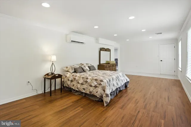 a spacious bedroom with a bed and wooden floor