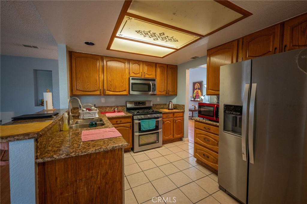 7444 Webster Street Highland, CA 92346 - Photo 12 of 37 a kitchen with stainless steel appliances granite countertop a refrigerator stove and sink