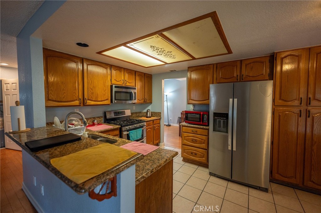 7444 Webster Street Highland, CA 92346 - Photo 13 of 37 a kitchen with stainless steel appliances granite countertop a refrigerator a sink dishwasher a stove with wooden cabinets
