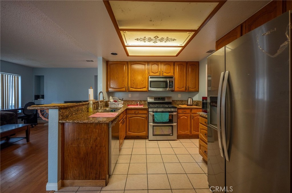 7444 Webster Street Highland, CA 92346 - Photo 10 of 37 a kitchen with stainless steel appliances granite countertop a stove refrigerator and a microwave