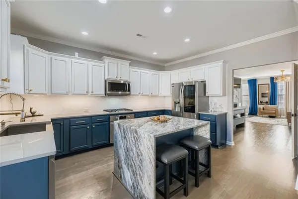 a kitchen with stainless steel appliances granite countertop a table chairs sink refrigerator and cabinets