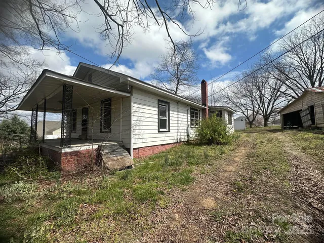 a backyard of a house with table and chairs under an umbrella