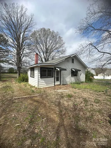 a front view of house with yard and trees in the background