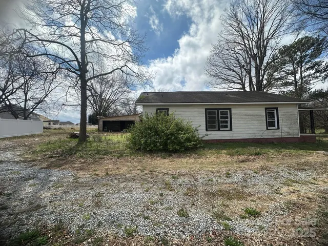 a backyard of a house with plants and large tree