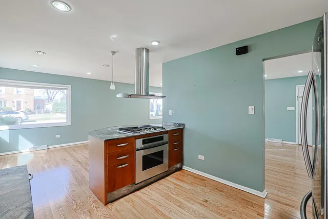 a kitchen with stainless steel appliances wooden floor and large window
