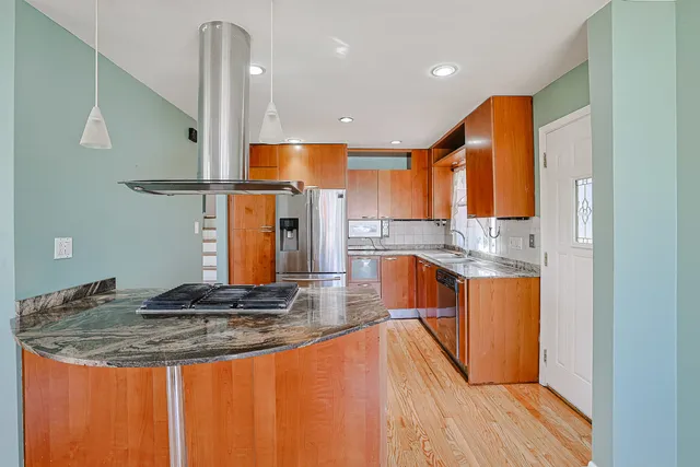 a kitchen with stainless steel appliances granite countertop a sink a stove and a refrigerator