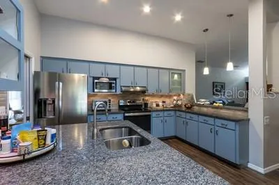 a kitchen with stainless steel appliances granite countertop a sink refrigerator and microwave