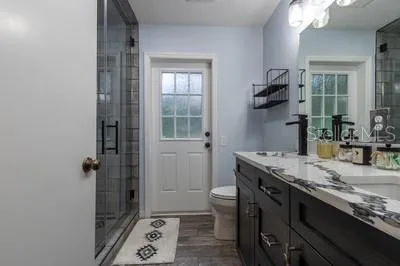 a bathroom with a granite countertop sink a mirror and a shower