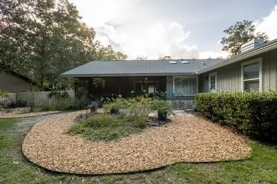 a view of a house with brick walls plants and large trees