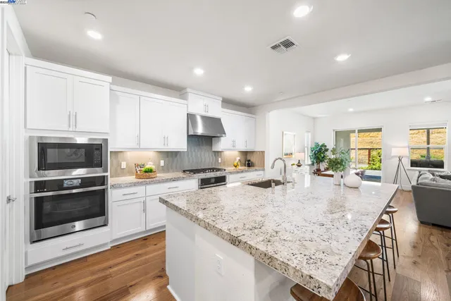 a large kitchen with granite countertop a stove top oven a sink a counter space and cabinets