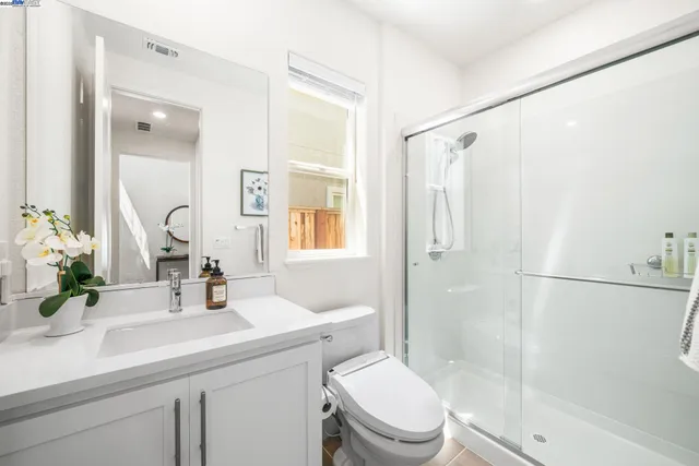 a bathroom with a sink a mirror a toilet and shower