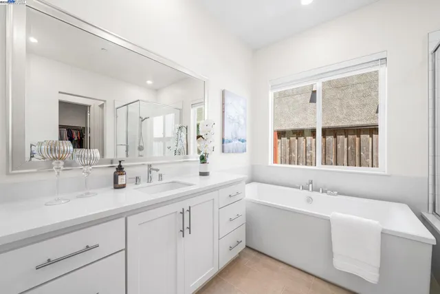 a bathroom with double vanity sinks a large mirror and a bathtub