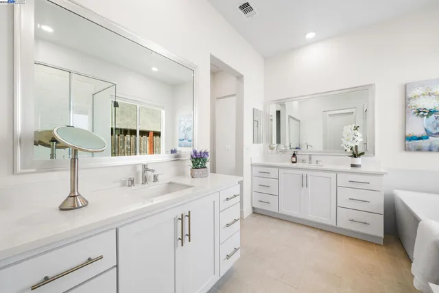 a spacious bathroom with a double vanity sink a mirror and next to a window