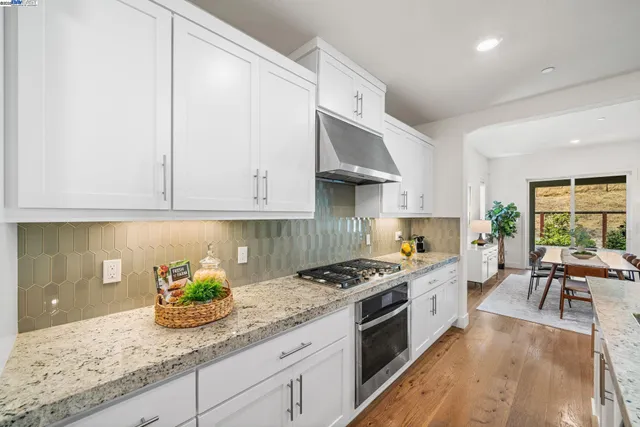 a kitchen with stainless steel appliances granite countertop a stove a sink and a white cabinets