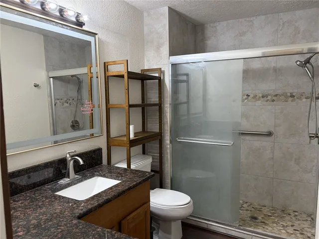 a bathroom with a granite countertop shower toilet and sink