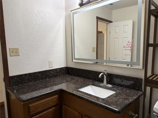 a bathroom with a granite countertop sink and a mirror